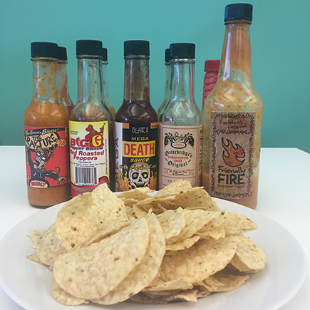 A line up of our favorite hot sauces with a plate of chips.